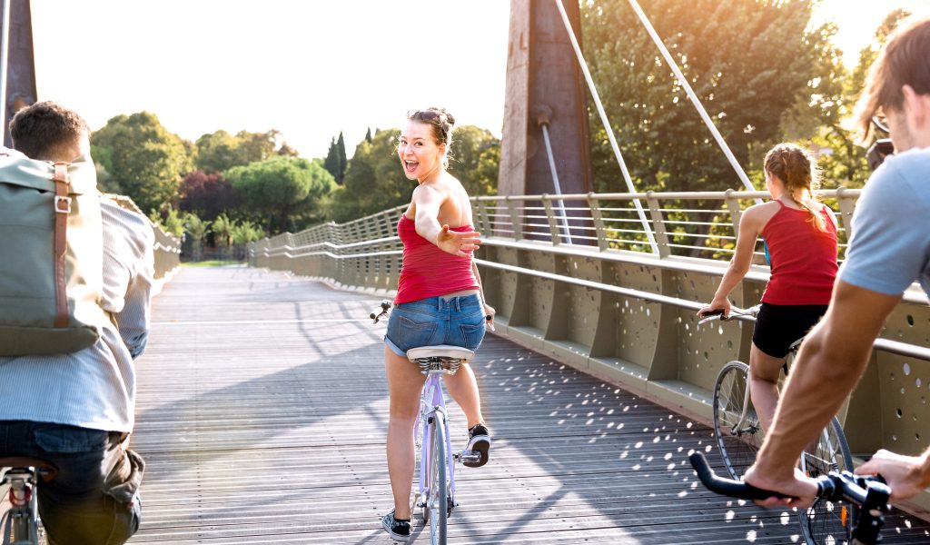 Happy friends millennial having fun riding bike at city park - F